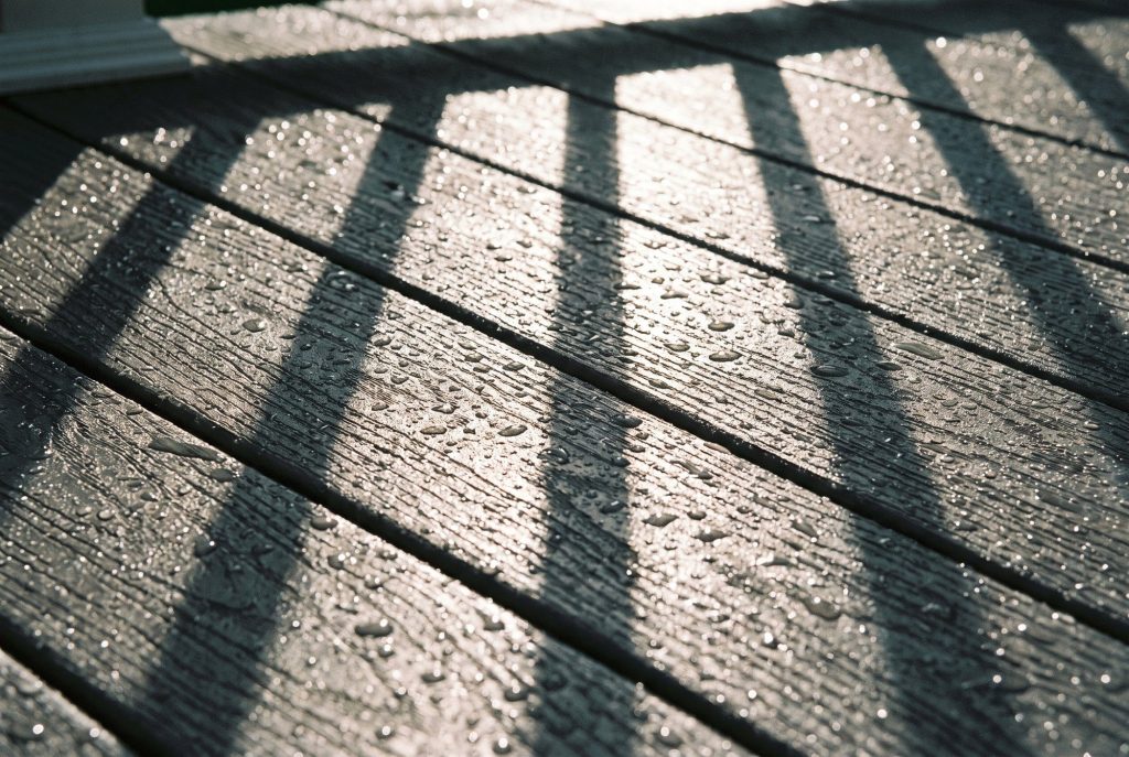 Wet composite deck boards with railing shadows after rain